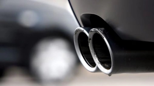 Close-up of twin chrome exhaust pipes on a dark vehicle undercarriage, highlighting vehicle emission output