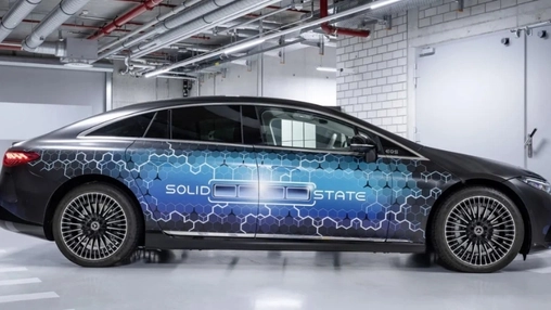 Side profile of a black Mercedes-Benz EQS with a blue hexagonal wrap and SOLID STATE text parked indoors