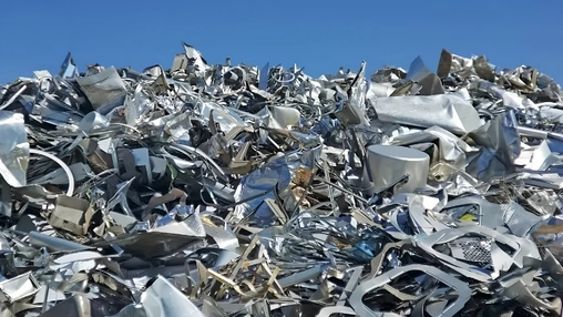 Close up view of shredded aluminum and steel scrap forming a dense metallic heap against an open sky