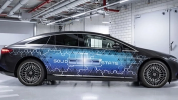 Side profile of a black Mercedes-Benz EQS with a blue hexagonal wrap and SOLID STATE text parked indoors